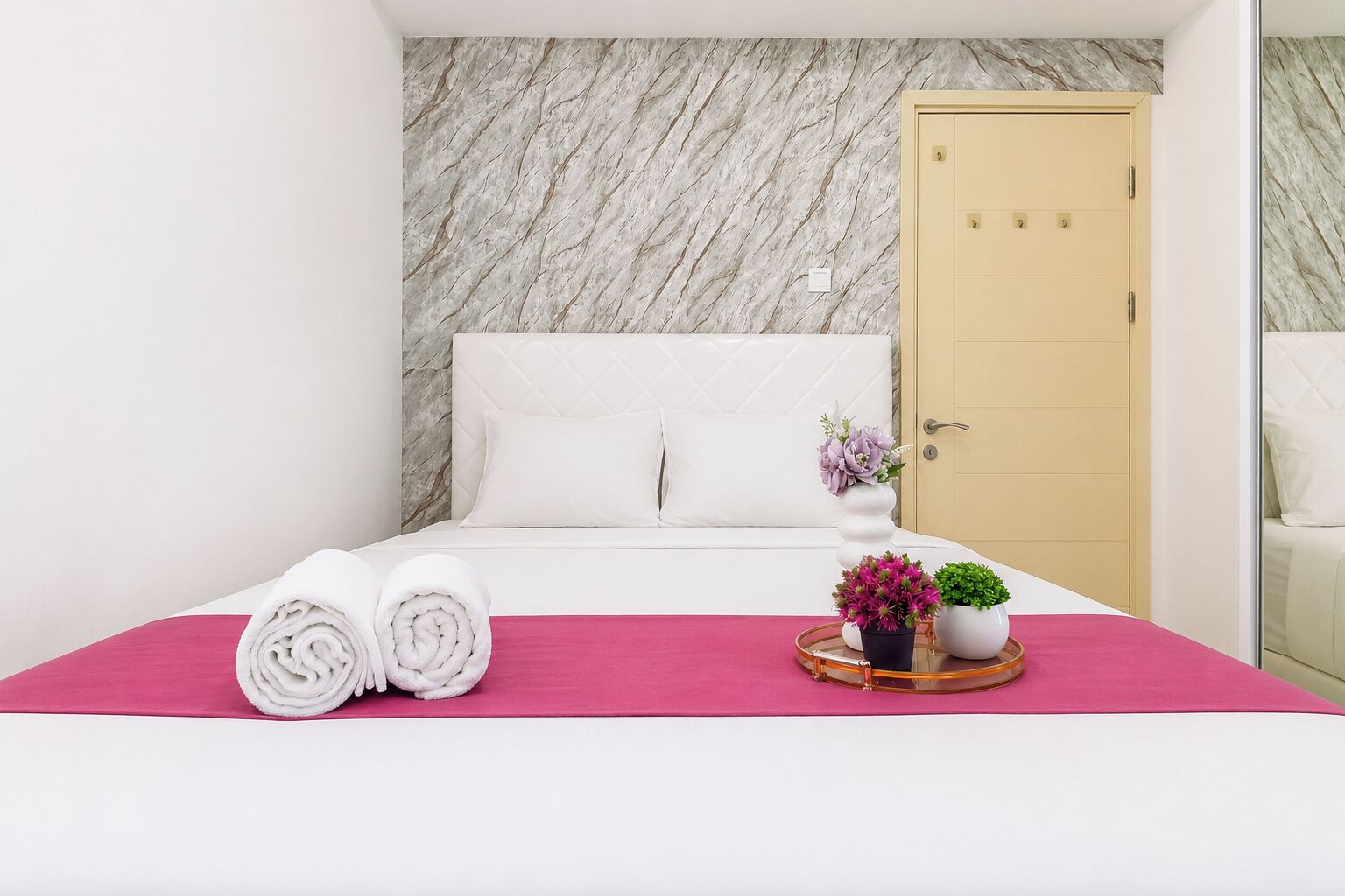 Una habitación de hotel con una cama, una puerta y un espejo.