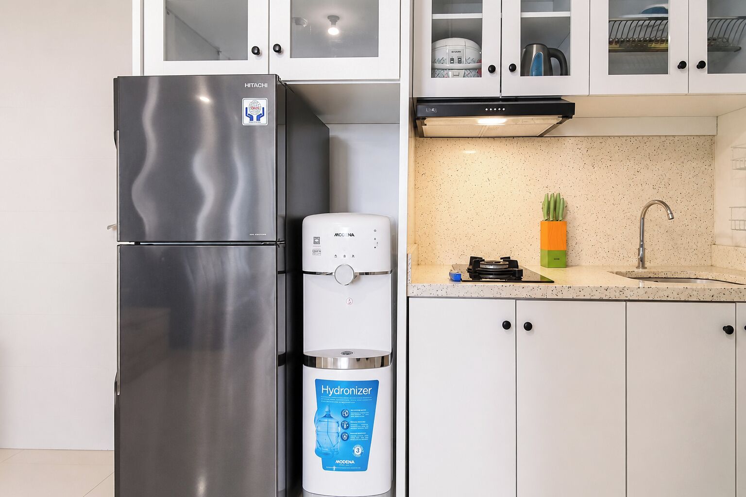 A kitchen with a stainless steel refrigerator, a water dispenser, and a countertop with a sink and a cutting board.