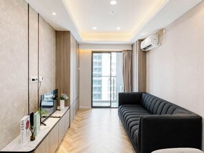 A modern living room with a sofa, a TV, and a cabinet. - Serene Wooden Touch 1Br At Apartemen Daan Mogot City (Jakarta)