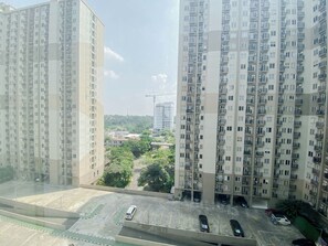A high-rise residential building with multiple balconies and a parking area below. - Warm And Cozy 2Br At Apartment Podomoro Golf View (Depok)