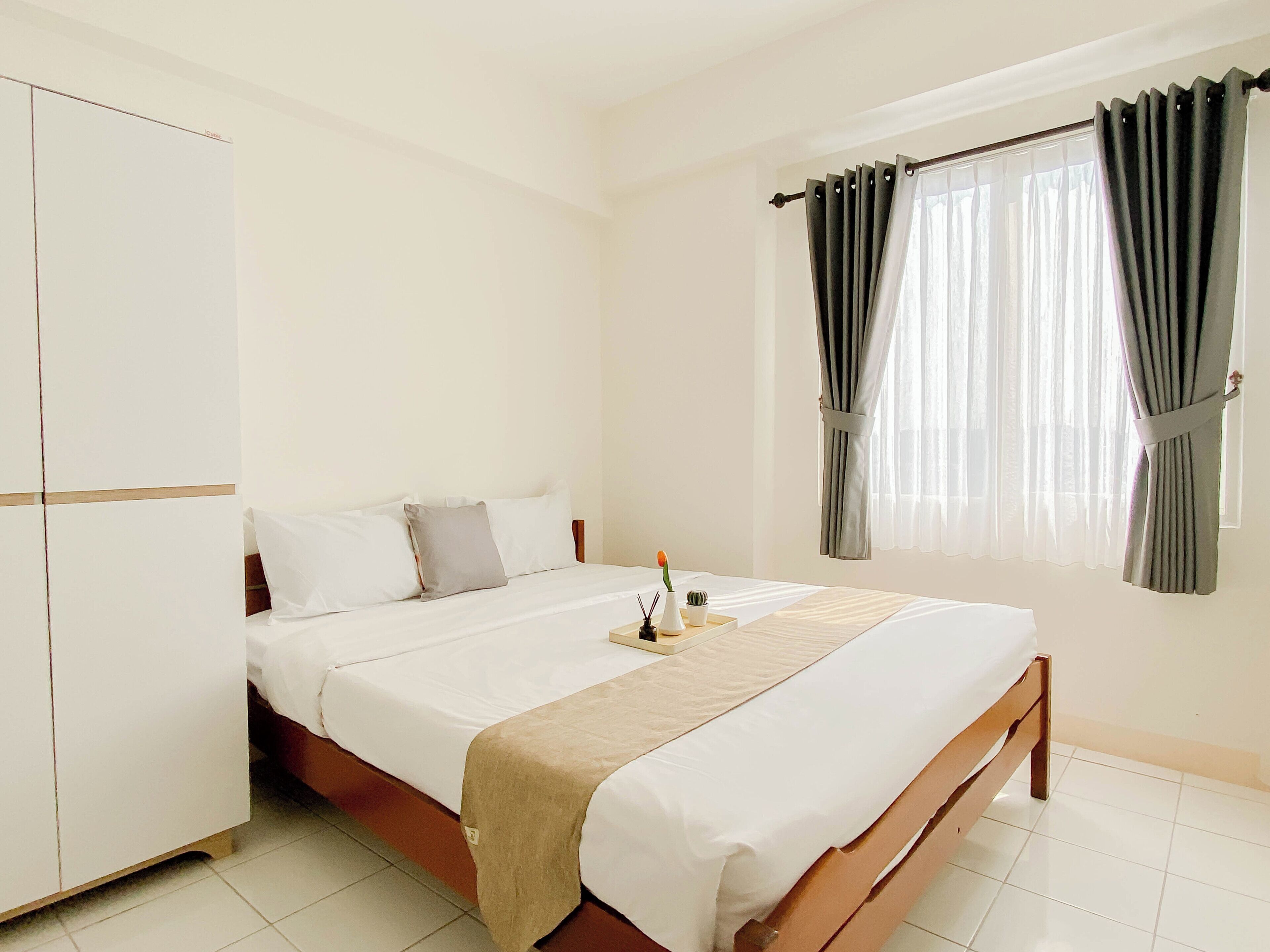 Un dormitorio con cama, armario y ventana con cortinas.