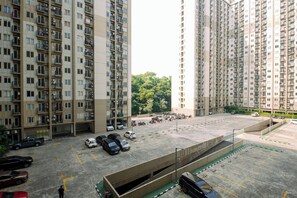 A multi-story residential building with a parking area in front. - Warm And Homey 2Br Apartment Podomoro Golf View (Depok)