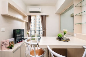 Un espacio habitable compacto con kitchenette, comedor, televisor y balcón con vistas a la ciudad.