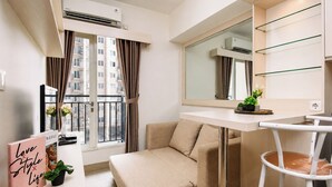 A modern apartment with a sofa, a small table, a mirror, and a view of the city through large windows. - Warm And Homey 2Br Apartment Podomoro Golf View (Depok)