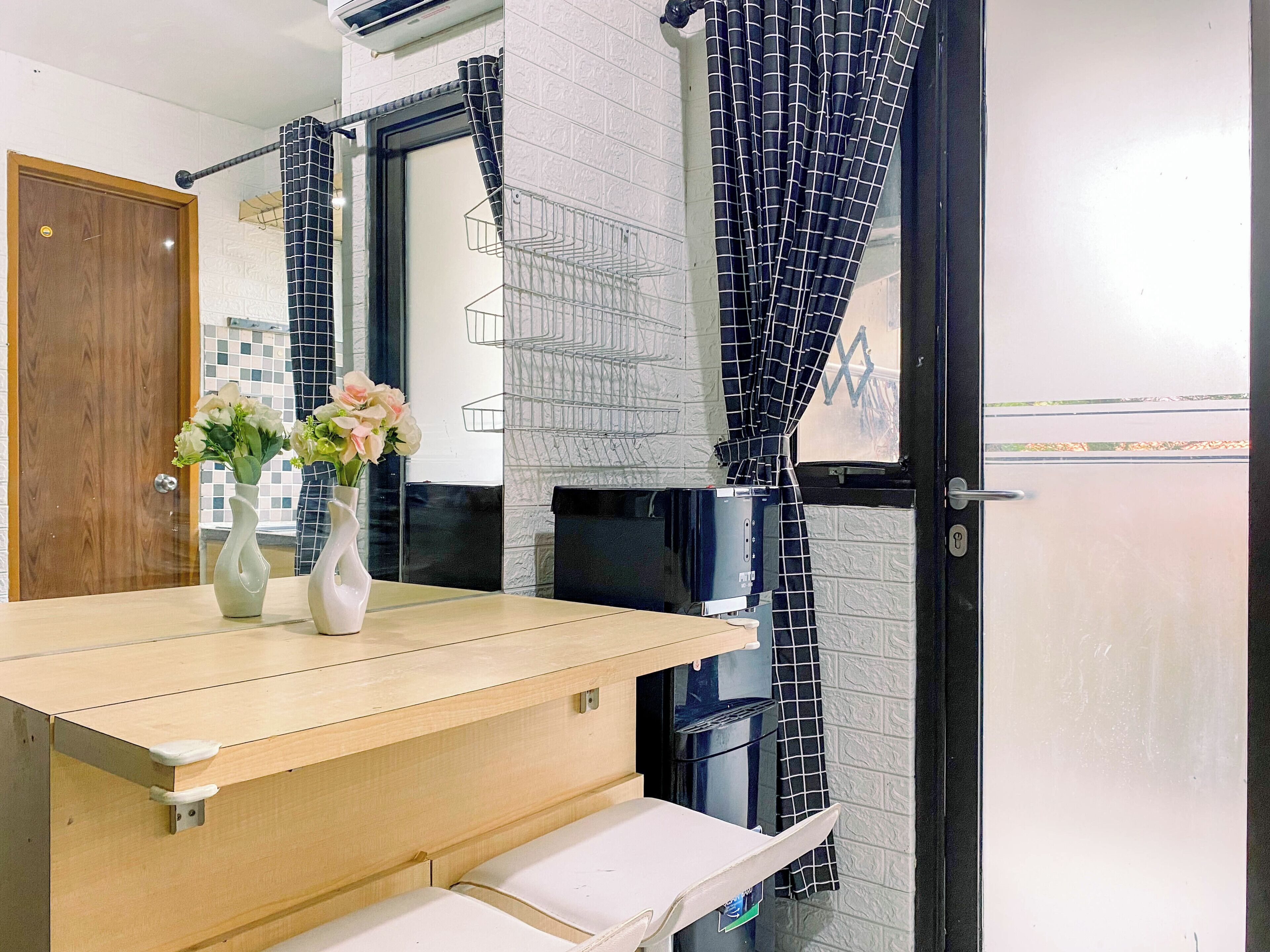 A bathroom with a wooden vanity, two vases with flowers, a towel rack, and a shower curtain.