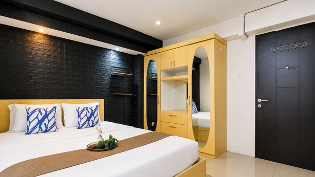 A modern bedroom with a bed, a wardrobe, and a door. - Good Warm Studio Room At Apartment Kebagusan City (Jakarta)