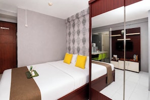 A modern hotel room with a large bed, a desk, and a mirror. - Strategic Location Studio At Apartment Kebagusan City (Jakarta)