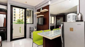Una cocina moderna con una mesa de vidrio, un refrigerador Sharp y vistas a un área residencial.