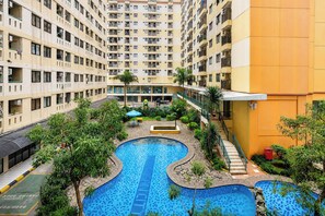 A residential building with multiple balconies, a central swimming pool, and surrounding greenery. - Strategic Location Studio At Apartment Kebagusan City (Jakarta)