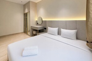 A hotel room with a bed, a desk, a chair, and a mirror. - Classic Roomy 2Br At Apartment Podomoro City Deli Medan (Medan)