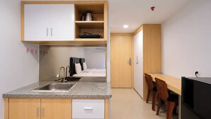 A compact kitchen with a sink, cabinets, and a dining area with a table and chairs. - Warm Stay In Studio Room At Apartment De Prima (Medan)