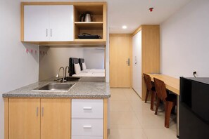 A compact kitchen with a sink, cabinets, and a dining area with a table and chairs. - Warm Stay In Studio Room At Apartment De Prima (Medan)