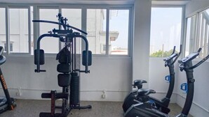 A gym with exercise equipment, including a multi-functional machine and stationary bikes. - Warm Stay In Studio Room At Apartment De Prima (Medan)