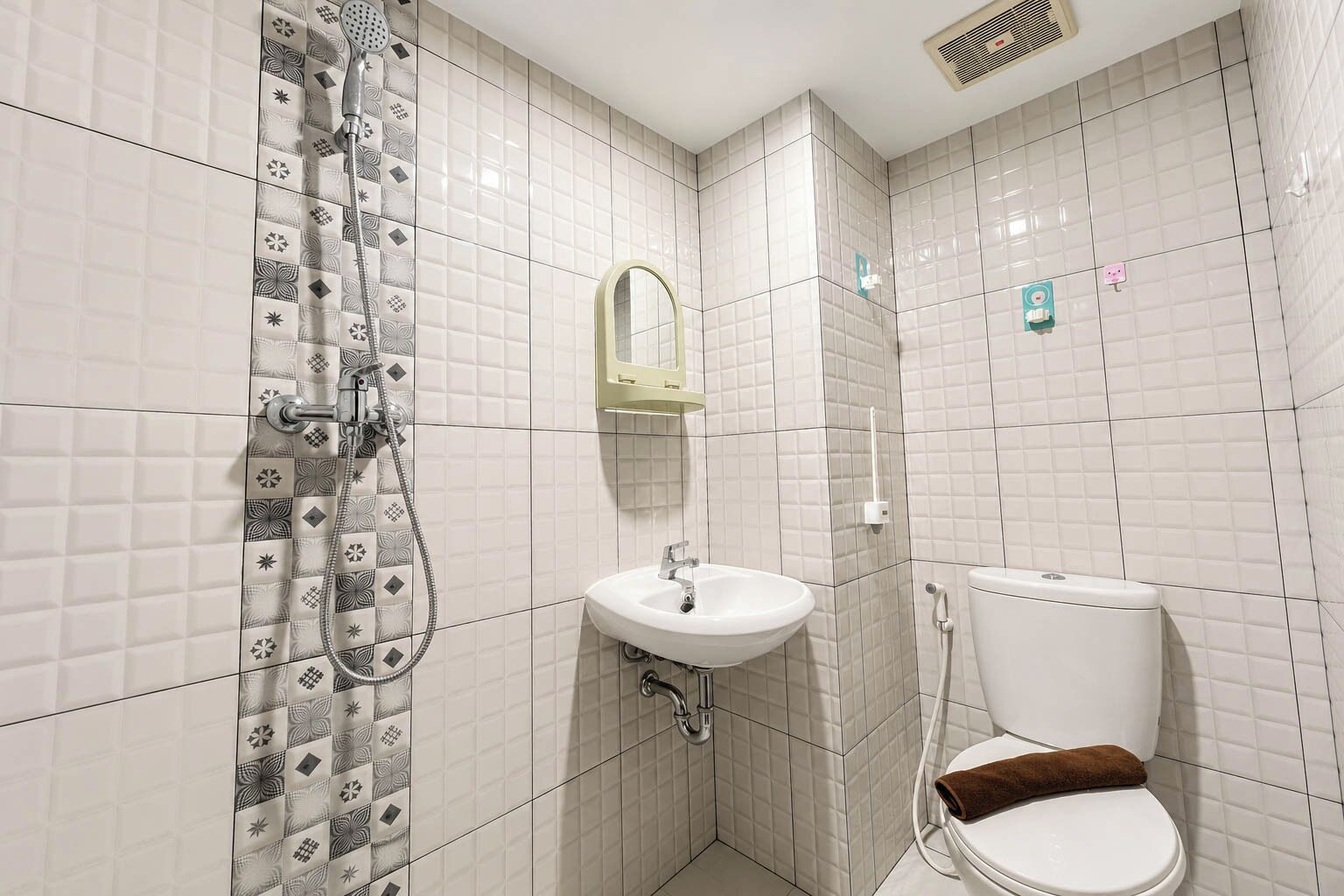 A bathroom with a shower, sink, mirror, toilet, and a towel.