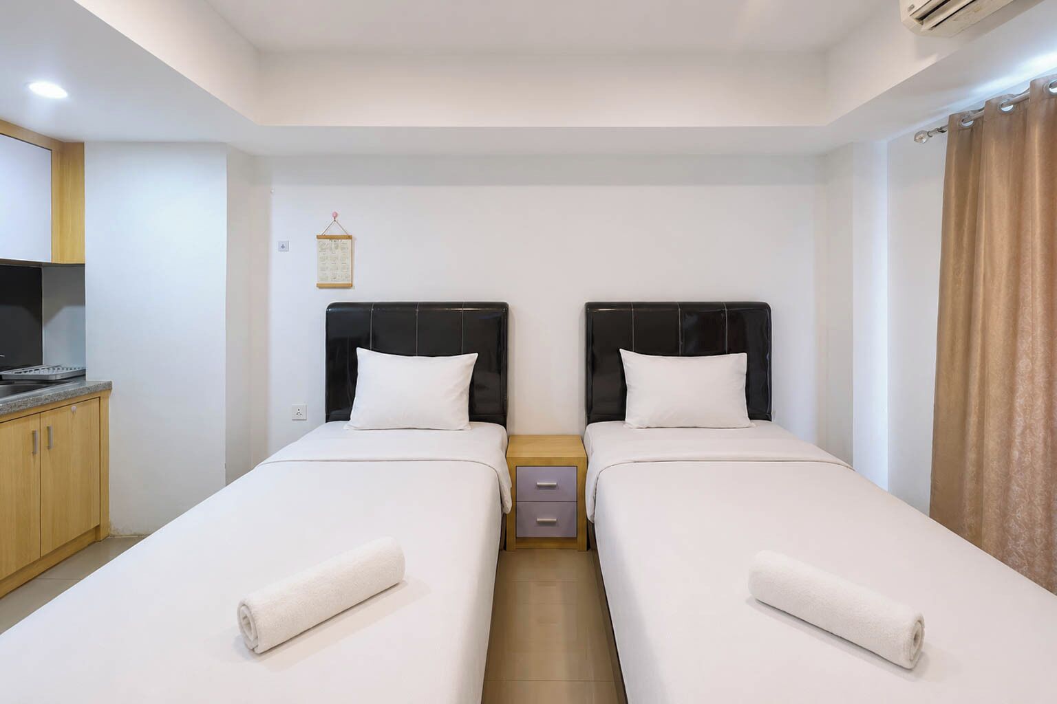 A twin room with two beds, a small table, a TV, and a wooden cabinet.
