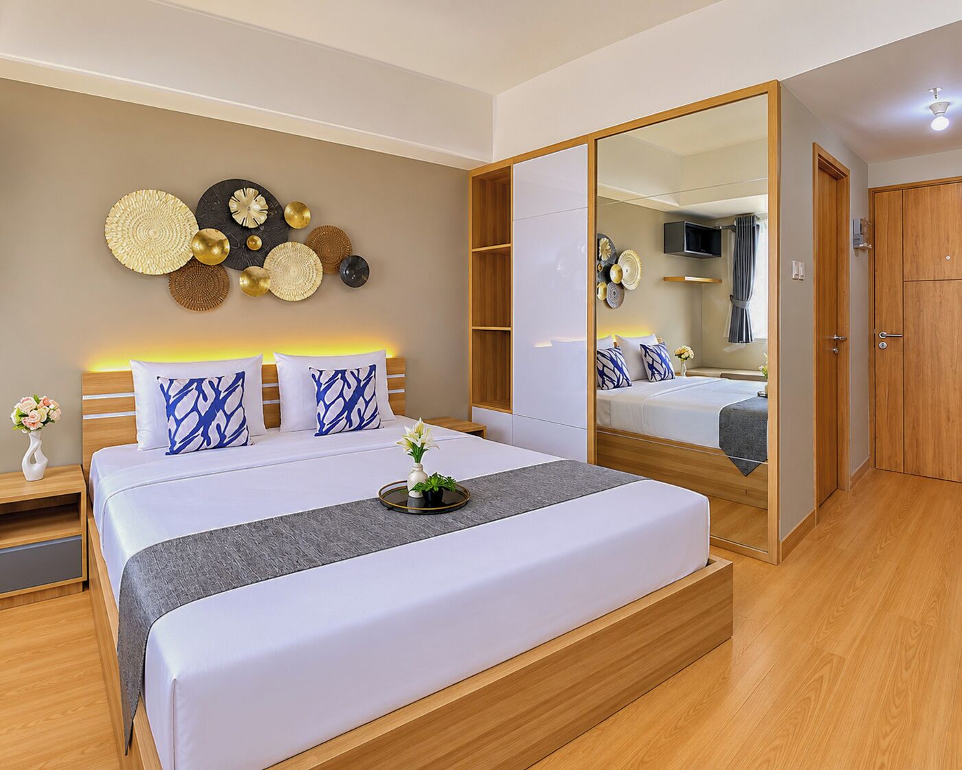Um quarto moderno com uma cama grande, mesas de cabeceira, um guarda-roupa e um espelho.