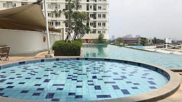 A swimming pool with a 60 cm depth marker, surrounded by a low wall and a building in the background.