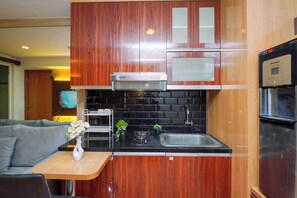 Uma cozinha compacta com armários de madeira, micro-ondas, fogão a gás e geladeira.