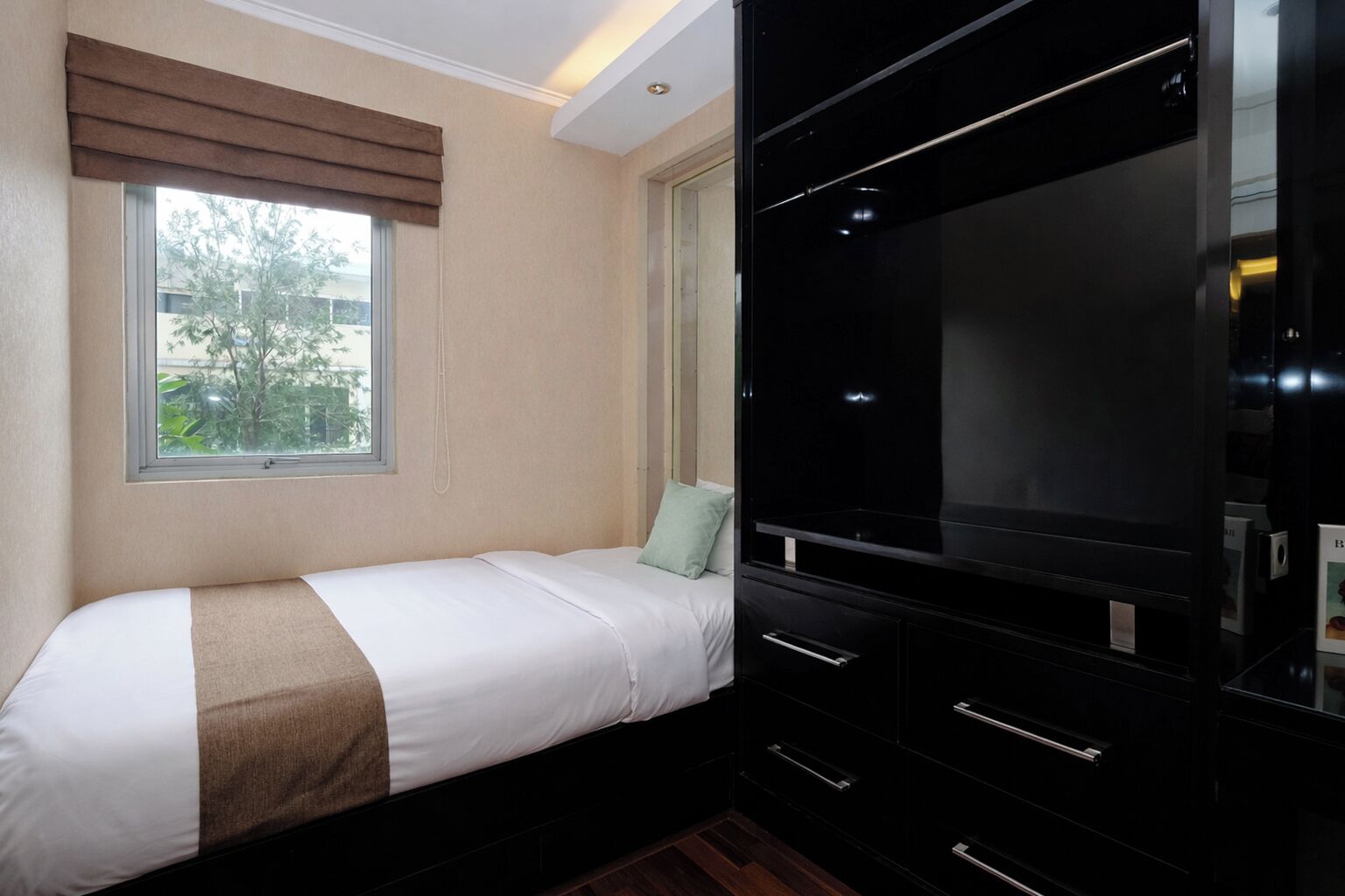 A bedroom with a bed, a window, a TV, and a wardrobe.