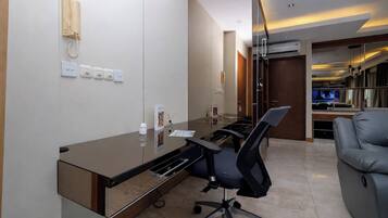 Um espaço de escritório moderno com uma mesa de vidro, cadeiras de escritório, um telefone e uma televisão ao fundo.