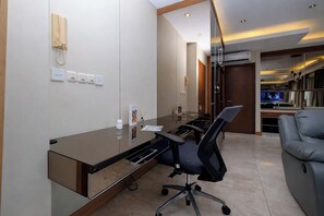 Um espaço de escritório moderno com uma mesa de vidro, cadeiras de escritório, um telefone e uma televisão ao fundo.