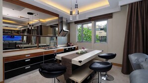 A modern kitchen with a dining area, bar stools, and a large mirror. - Warm Combined 3Br At Maple Park Sunter Apartment (Jakarta)