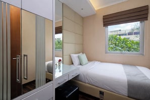 Ein Schlafzimmer mit einem Bett, einem Nachttisch, einem Spiegel und einem Fenster mit Blick auf Grünflächen.