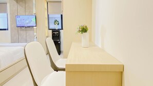 Habitación de hotel con cama, escritorio, silla, televisor y dispensador de agua.