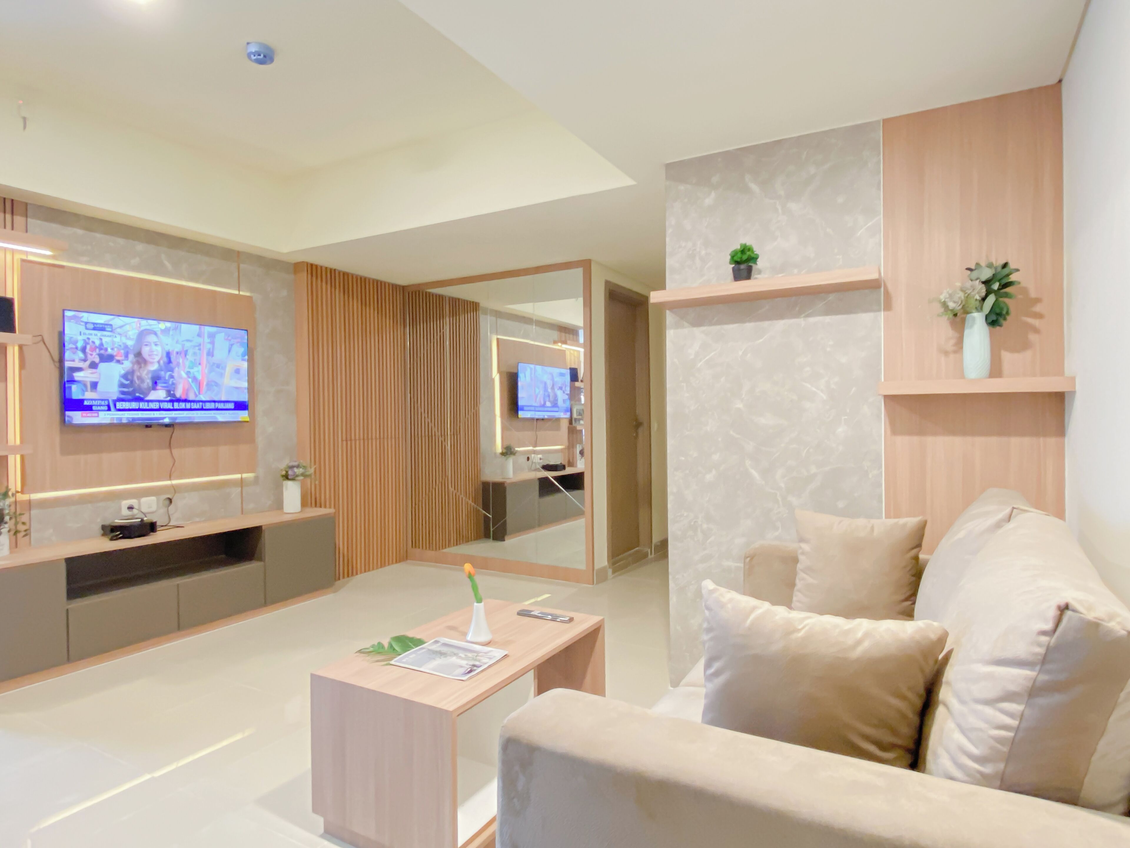 A modern living room with a sofa, a coffee table, a TV mounted on the wall, and a wooden partition.