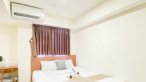 Een hotelkamer met een bed, een bureau, een airconditioner en een raam met gordijnen.
