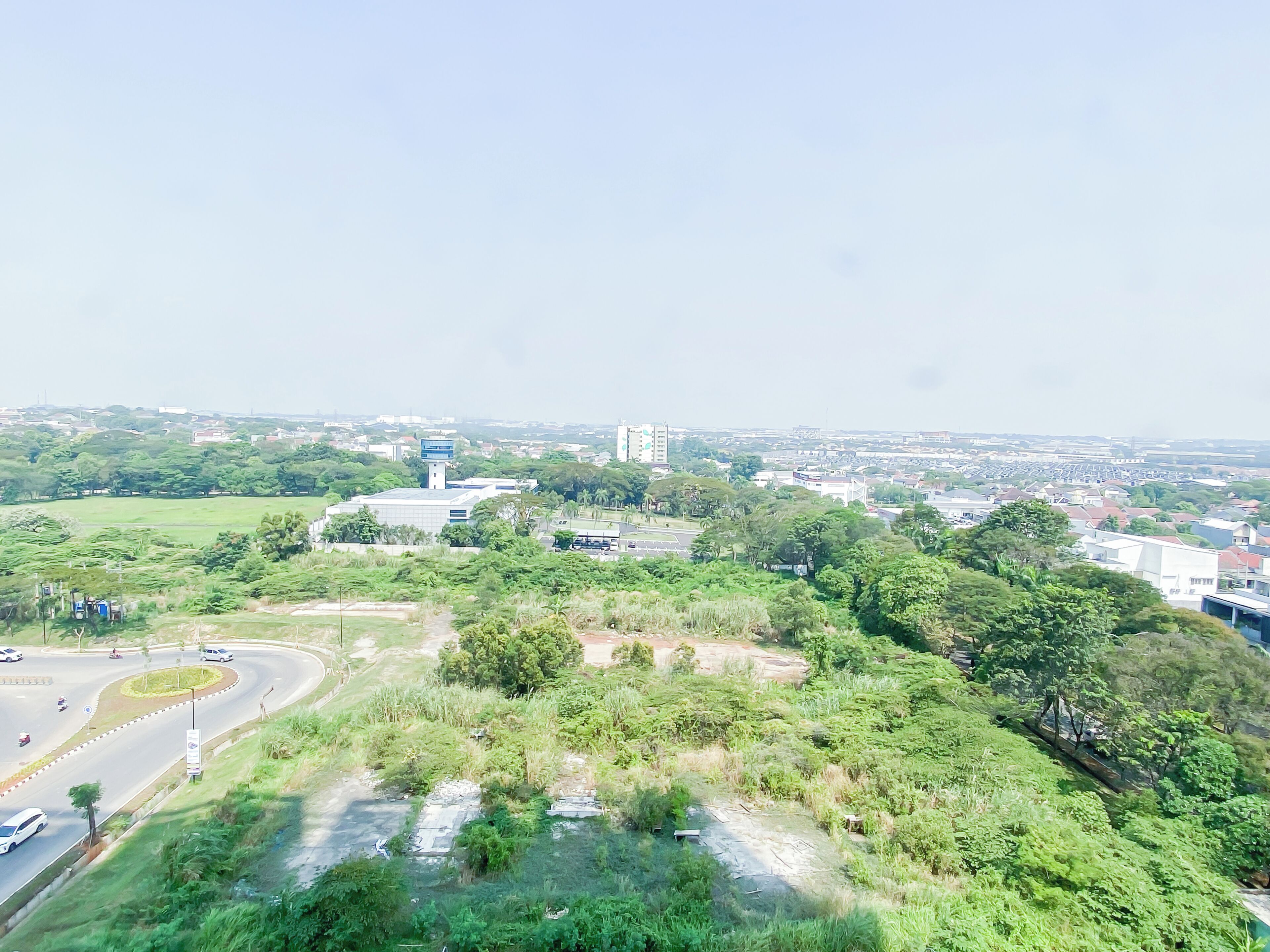 Une vue urbaine mettant en valeur un bâtiment imposant, un rond-point et la végétation environnante.