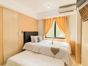A hotel room with a bed, curtains, an air conditioning unit, and a window. - Bright And Cozy Studio Room At Apartment Meikarta District 2 (Cikarang)