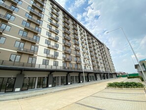 A multi-story residential building with balconies, a covered walkway, and a paved entrance area. - Bright And Cozy Studio Room At Apartment Meikarta District 2 (Cikarang)