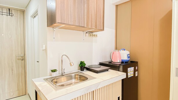 Una kitchenette compacta con un lavamanos, una pequeña encimera y un armario arriba.