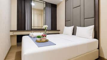 A hotel room with a large bed, a bedside table with a vase of flowers, and a mirror above the bed.