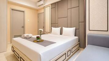 Habitación de hotel con una cama grande, una mesita de noche con un florero y un aire acondicionado de pared.