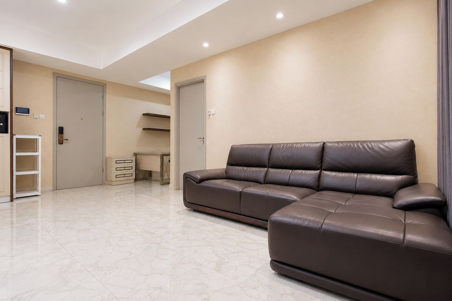 Un salon moderne avec un canapé en cuir marron, un bureau et un meuble de rangement.