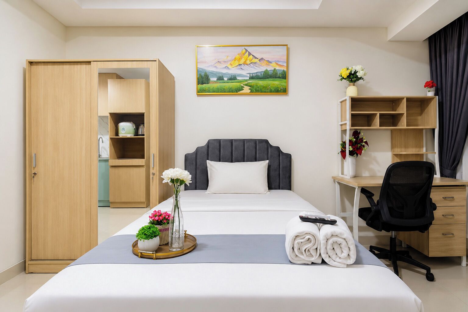 A hotel room with a bed, a desk, a chair, a wardrobe, and a painting on the wall.