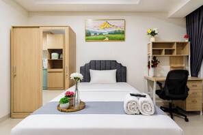Habitación de hotel con cama, escritorio, silla, armario y un cuadro en la pared.