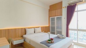 Habitació d'hotel amb llit, taula de nit i finestra amb cortines.