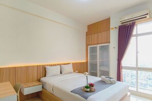Een hotelkamer met een bed, nachtkastje en een raam met gordijnen.