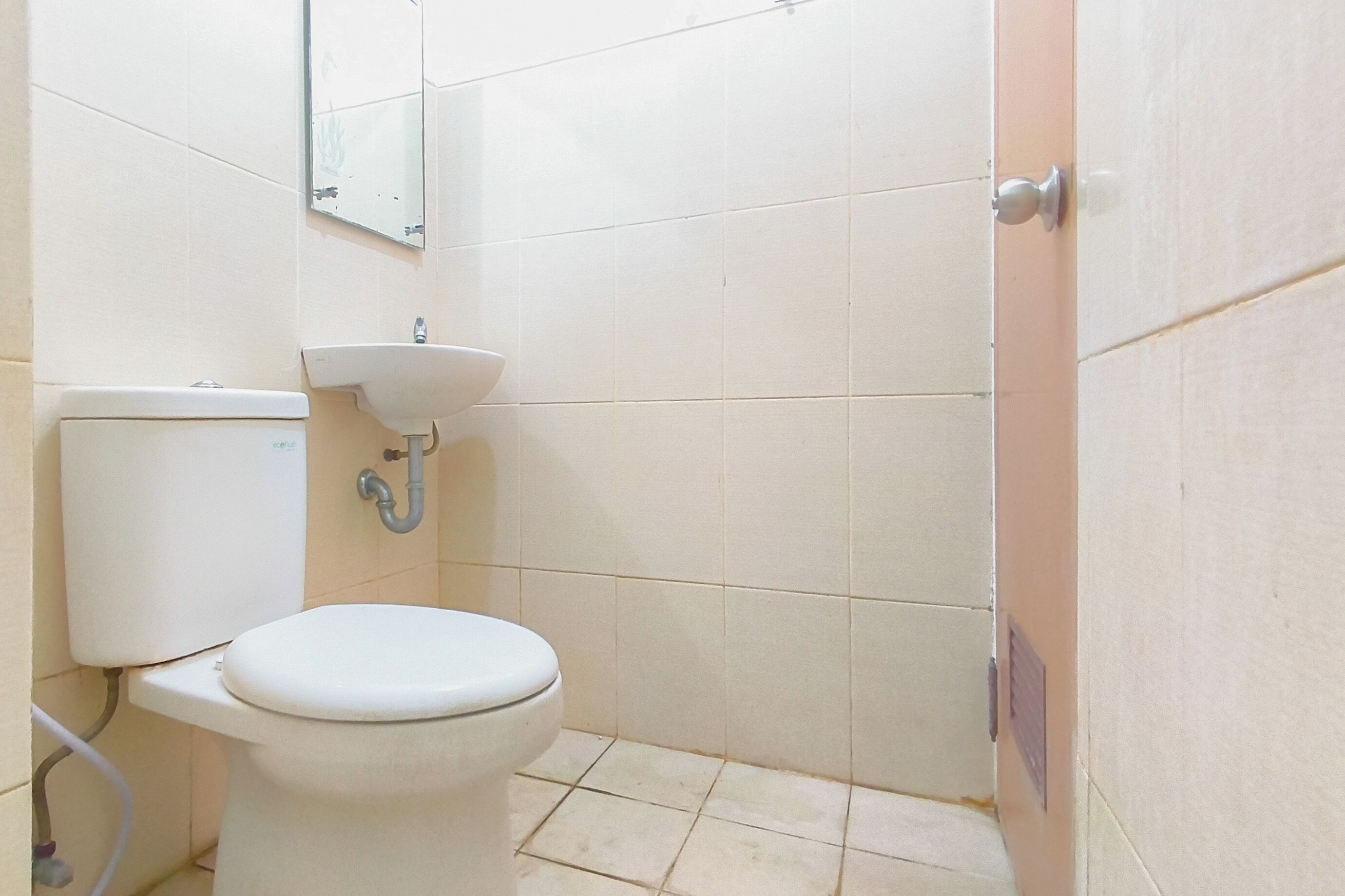 A small bathroom with a toilet, sink, and a mirror on the wall.