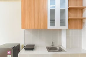 Een keuken met houten kastjes, een geïntegreerde spoelbak en een kleine koelkast.