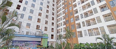 A multi-story residential building with balconies, a swimming pool, and surrounding greenery.