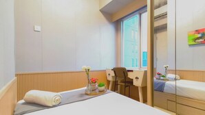 Et hotelværelse med seng, skrivebord, stol og et vindue.