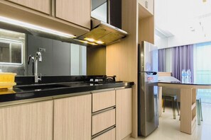 Une cuisine moderne dotée d’une hotte en acier inoxydable, d’un évier à deux bacs et d’un réfrigérateur encastré.