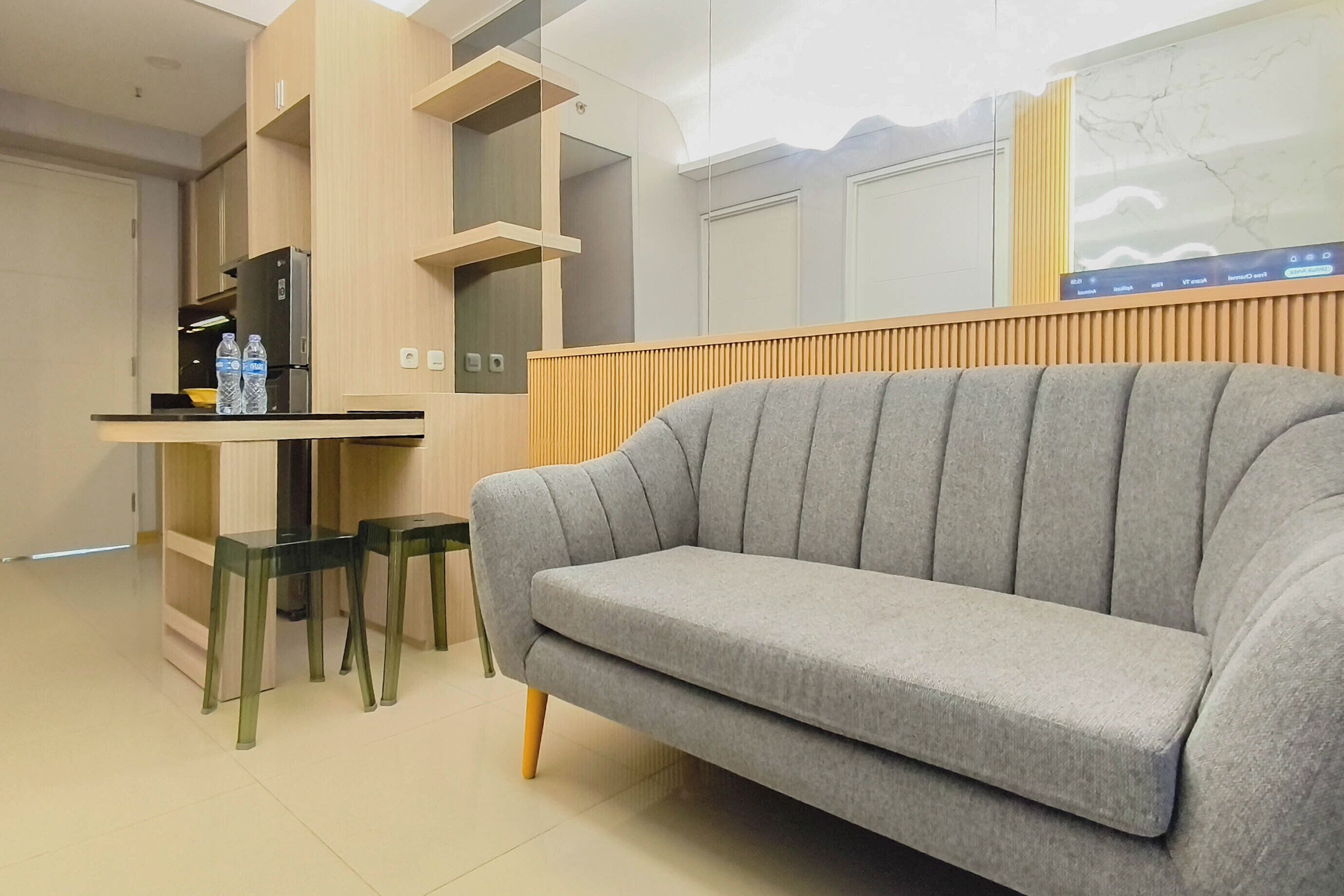 A modern living area with a grey sofa, a wooden cabinet, and a small table with water bottles.