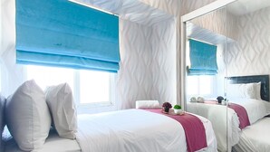 Ein Hotelzimmer mit zwei Betten, einem großen Spiegel und einem Fenster mit blauen Jalousien.