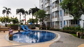 Ein Pool mit Rutsche, umgeben von Bäumen und einem mehrstöckigen Gebäude.