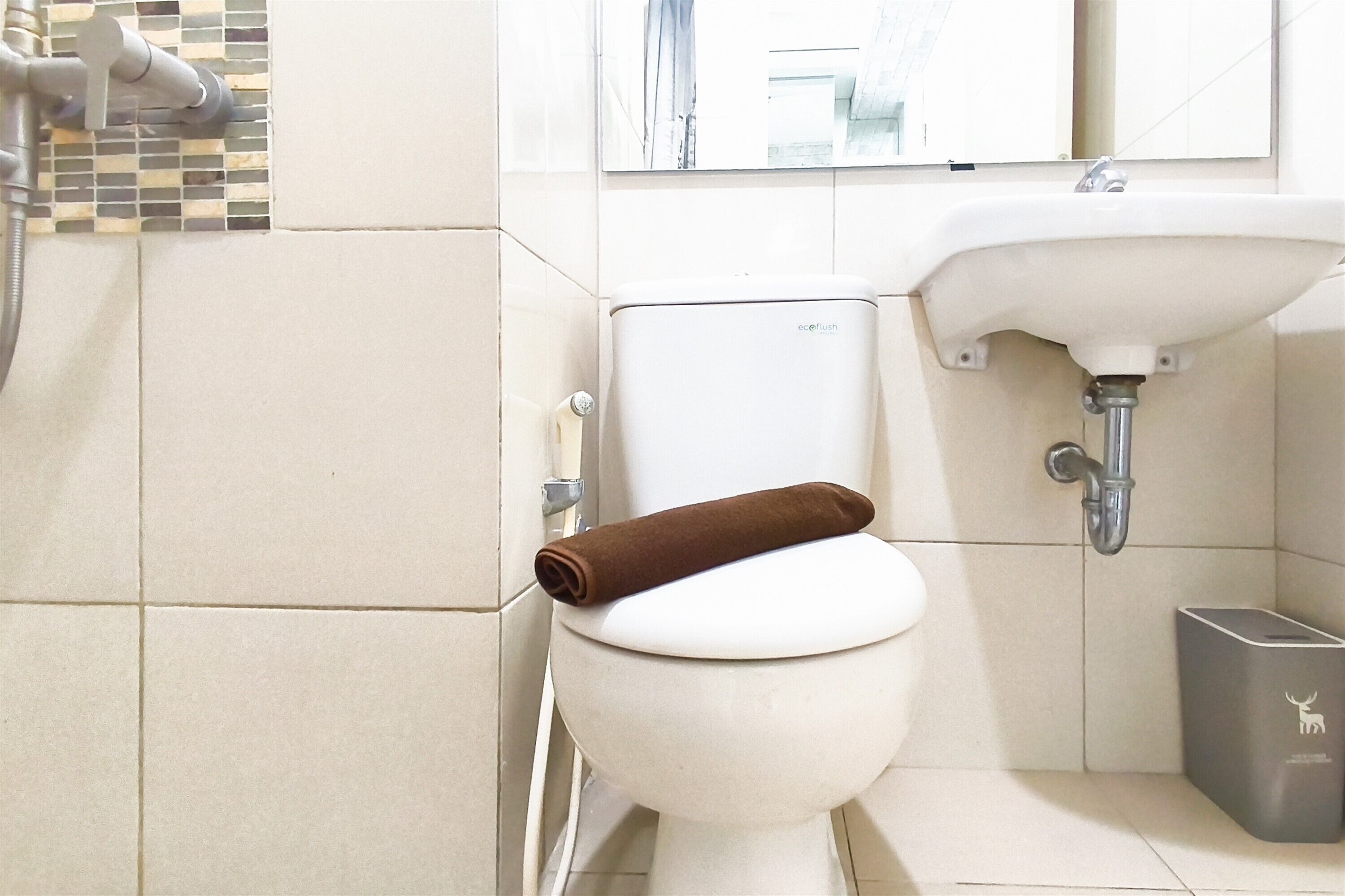 A bathroom with a toilet, sink, and a trash bin.